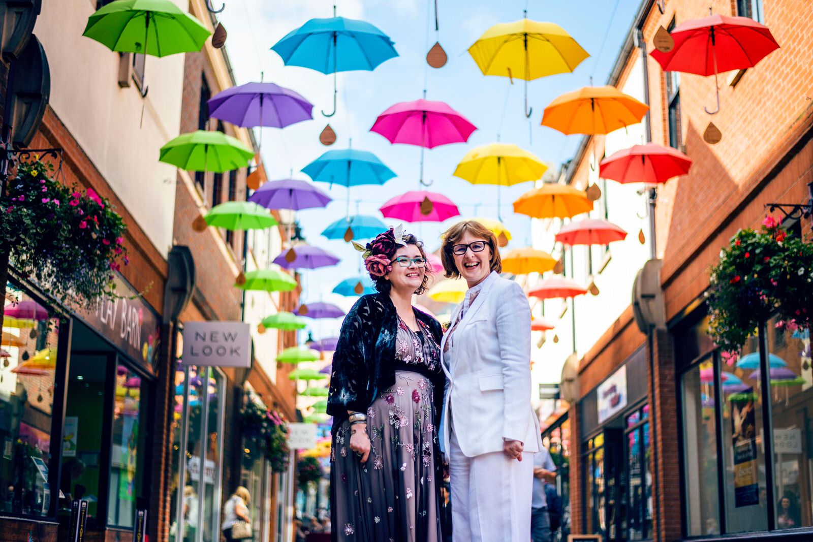 Two brides under a street full of umbrellas