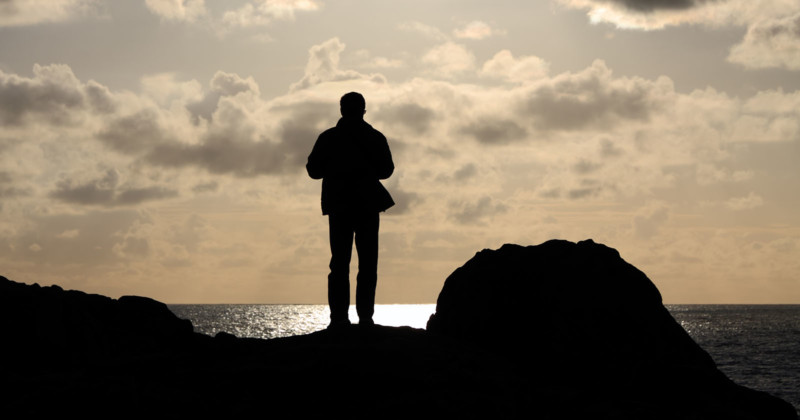 Silhouette of a man on a cliff watching the sea