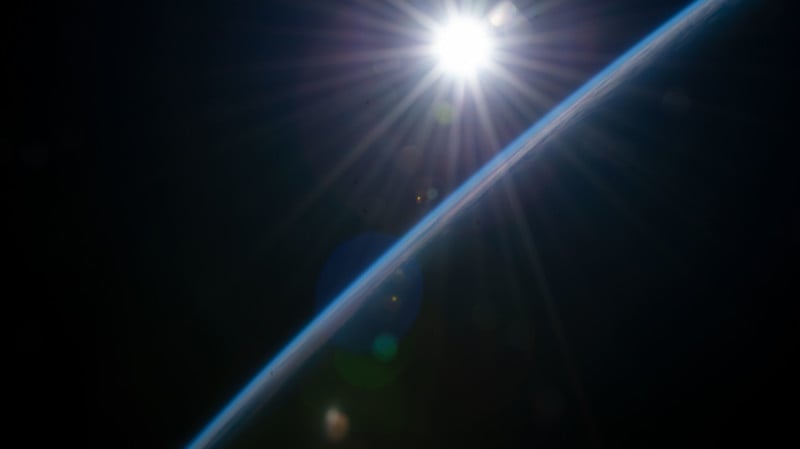 The first rays of an orbital sunrise illuminate the Earth's atmosphere