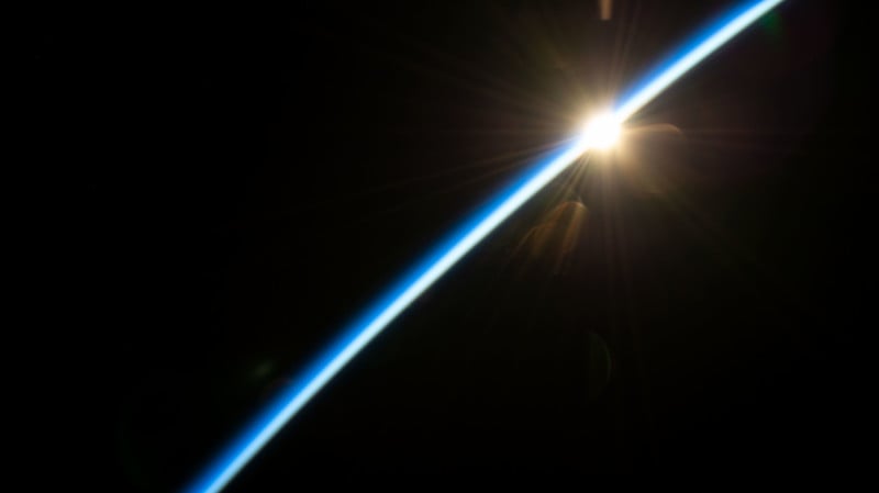 The first rays of an orbital sunrise illuminate the Earth's atmosphere