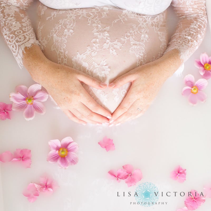 A milk bath photo with a woman making a hear with her hands on her belly