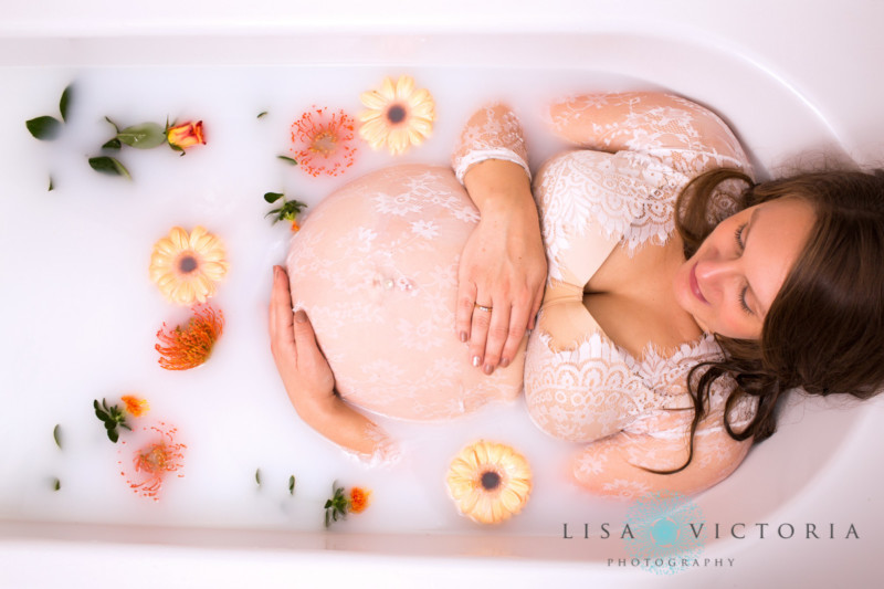 A pregnant woman in a milk bath with flowers around her
