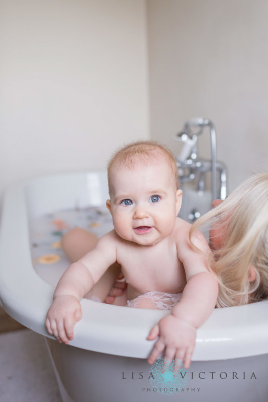 A baby looking over its mothers shoulder during a milk bath photo shoot