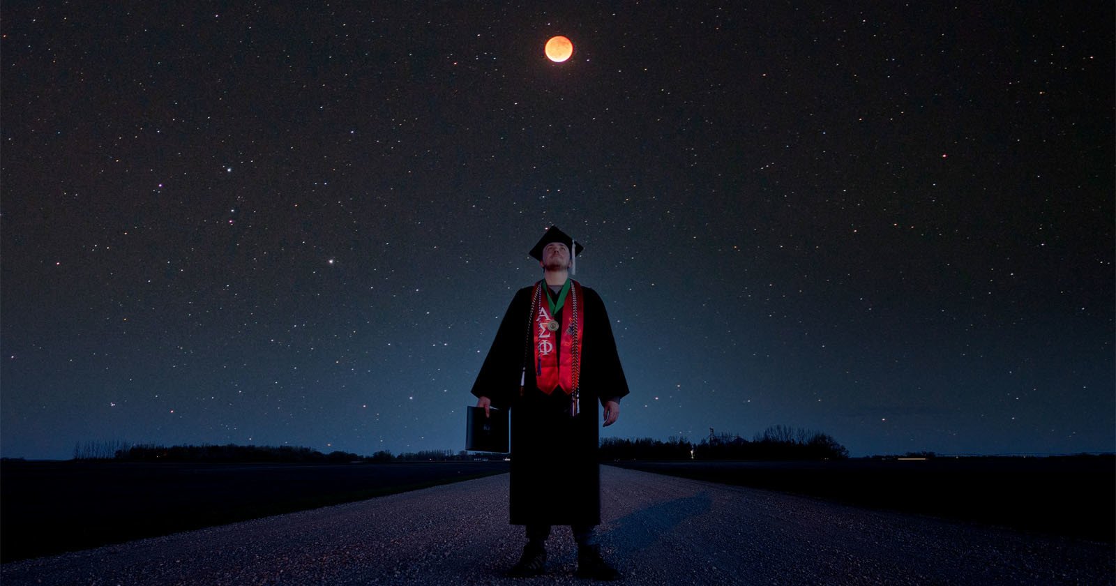 Astrophysics Student Takes Graduation Photo Under a Total Lunar Eclipse