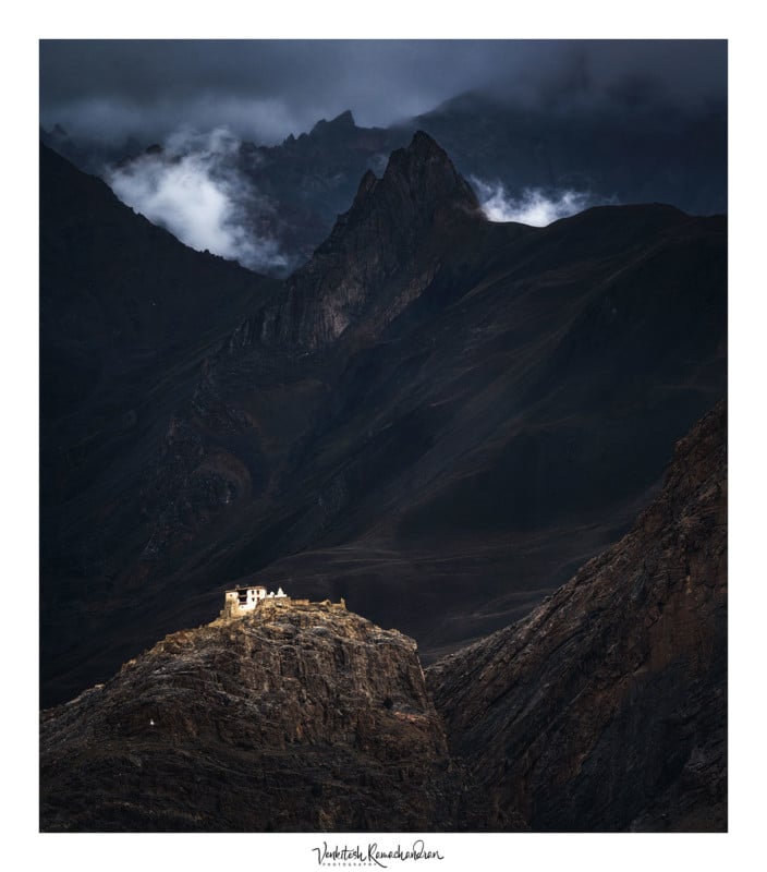 a structure on a hill with dark mountains in distance