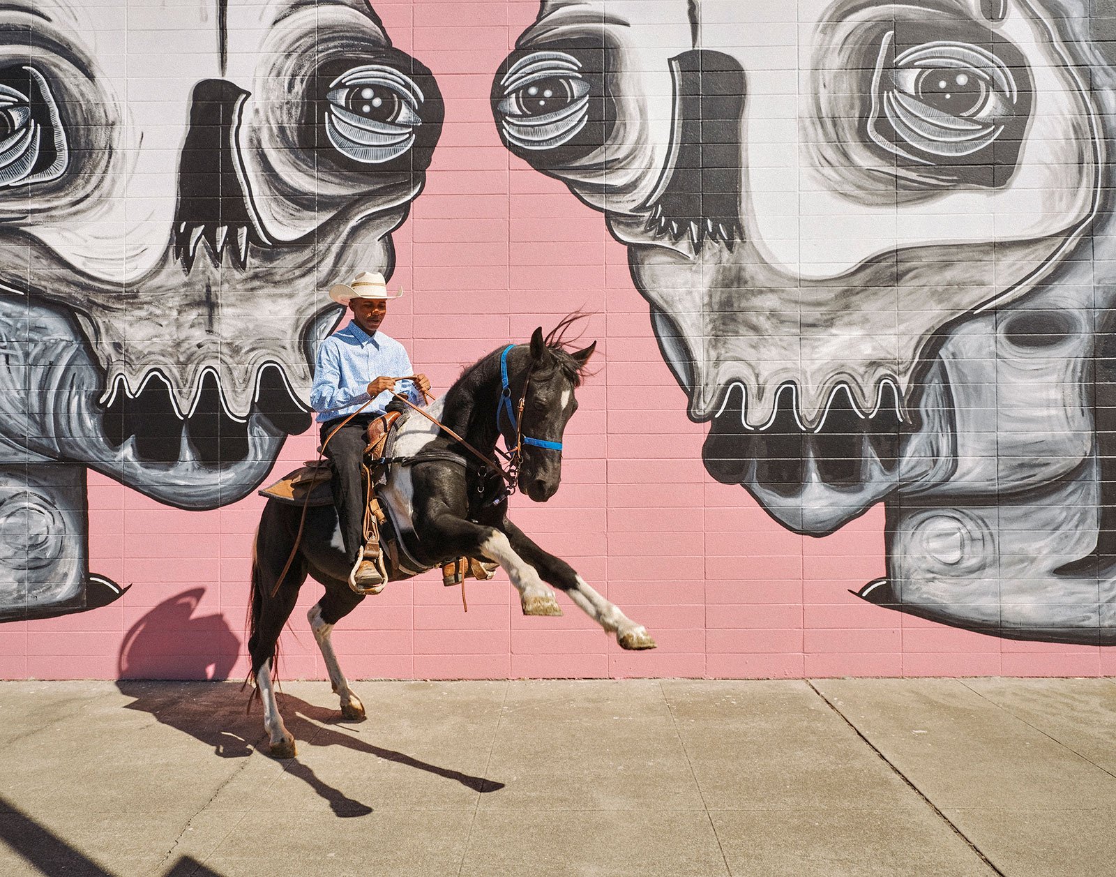 man riding horse with a mural behind him