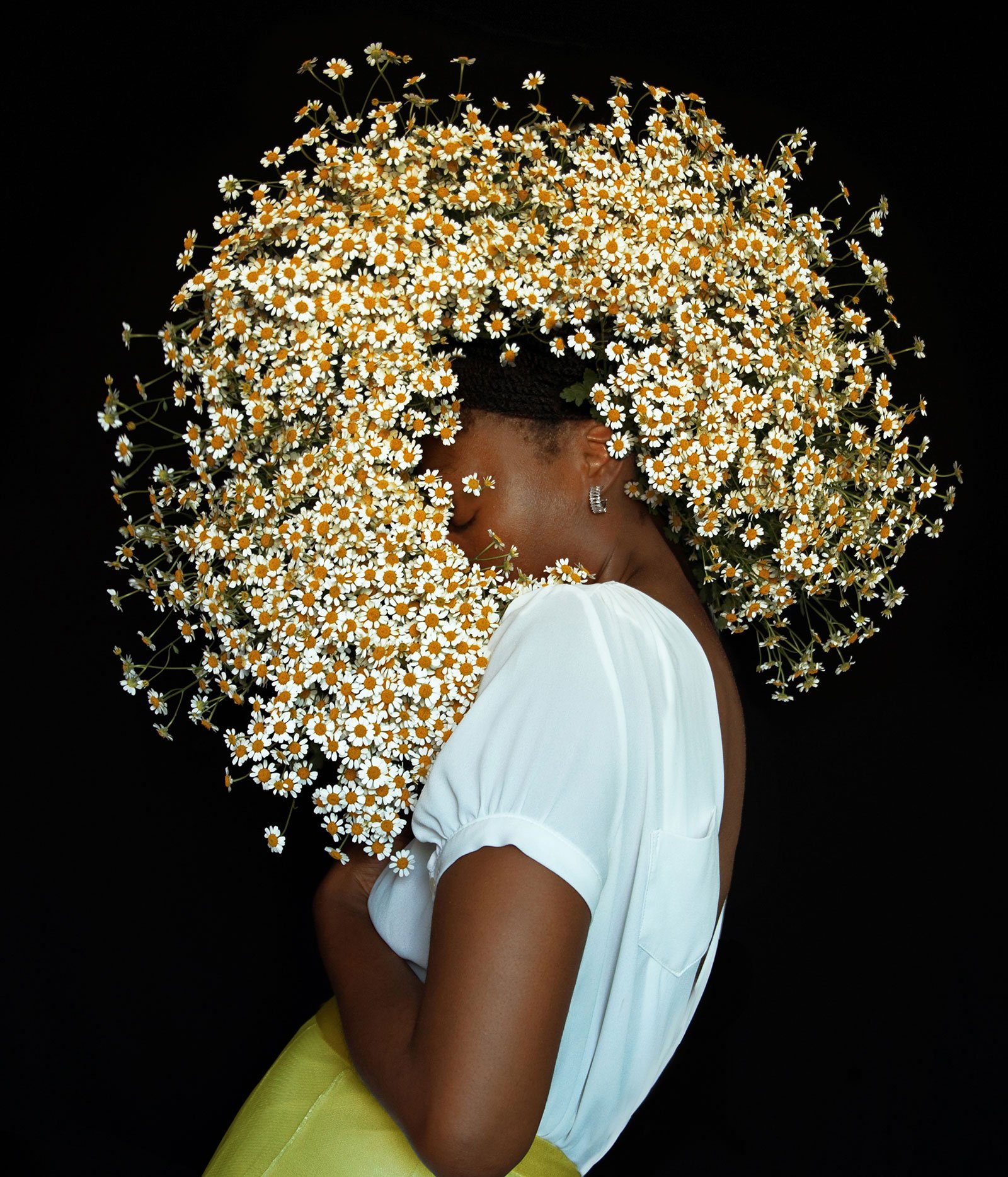 Woman with solid black background and flower afro