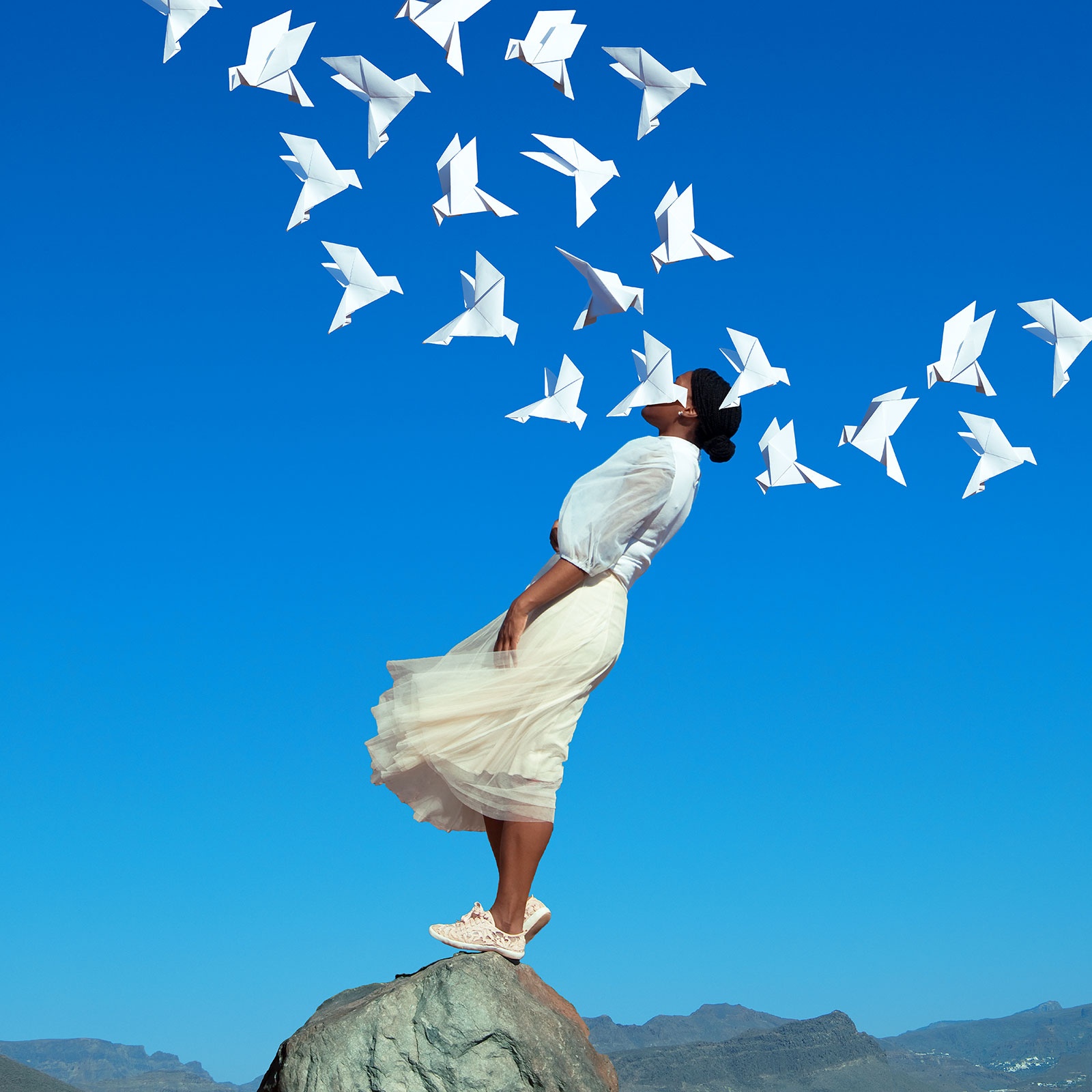 woman falling backwards and paper cranes fly above 