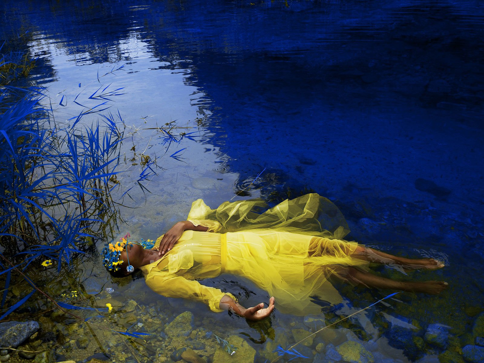 A woman in a yellow dress is floating in a puddle
