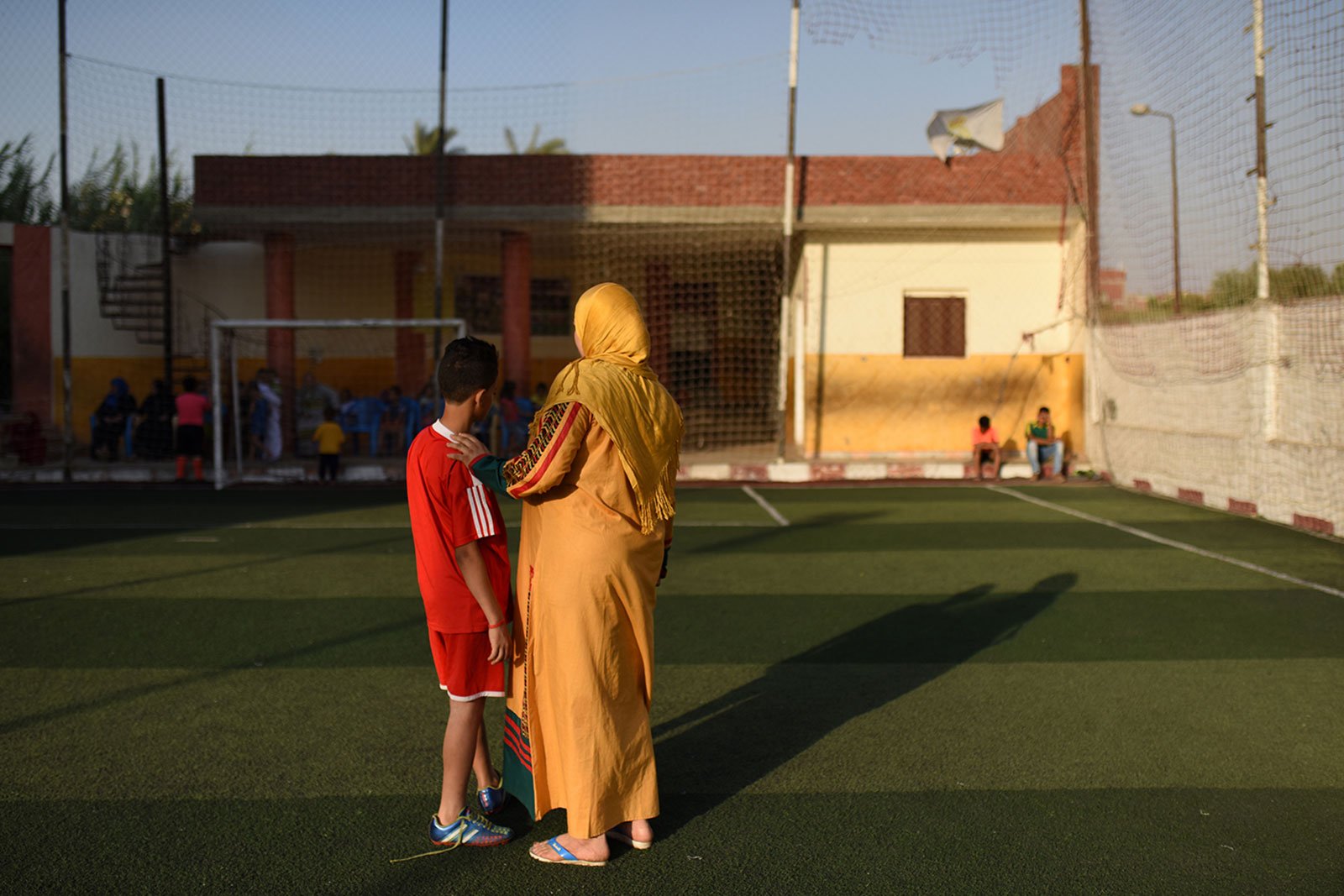 woman in hijab and child standing on a soccer field