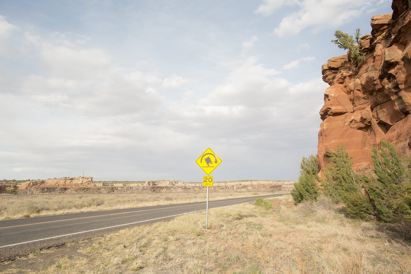 open road with yellow danger falling rocks sign 