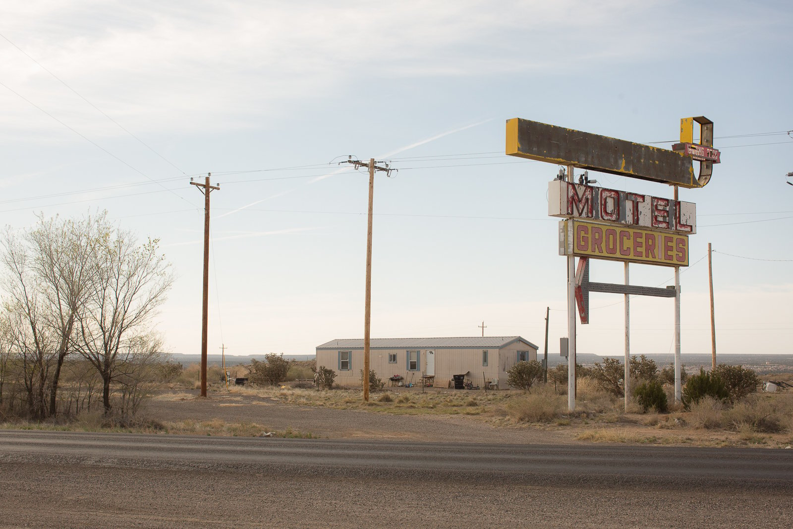 old neon sign and old home and power lines in the background 