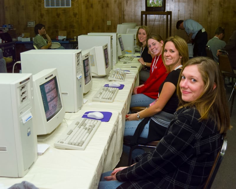 Four women sit in front of computers