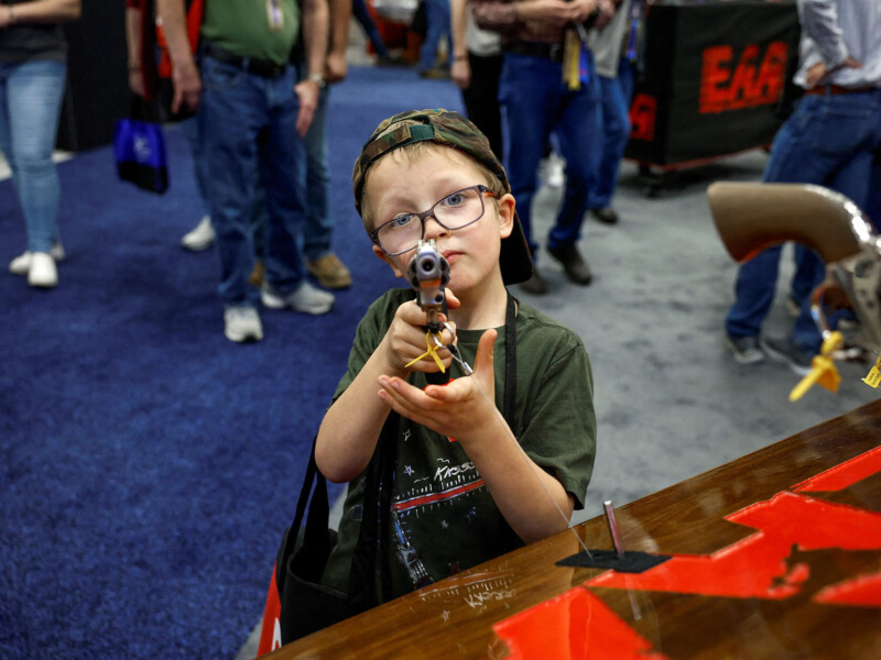 Young boy points gun at the camera