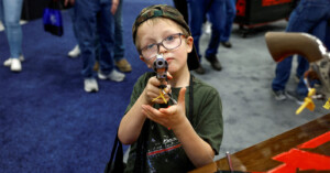 Young boy points gun at the camera