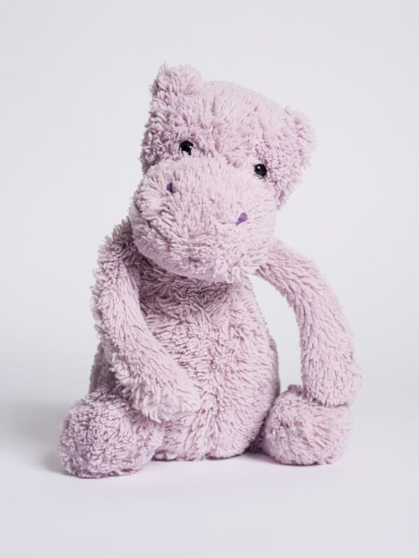 Purple, hippo stuffed animal sitting against plain white background 