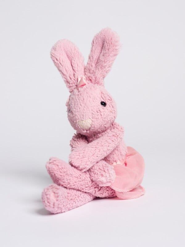 pink bunny stuffed animal sitting with crossed arms against plain white background 