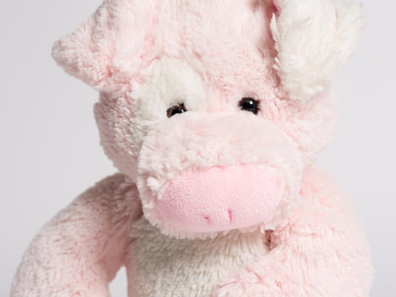 up close view of Pink hippo stuffed animal sitting against plain white background 