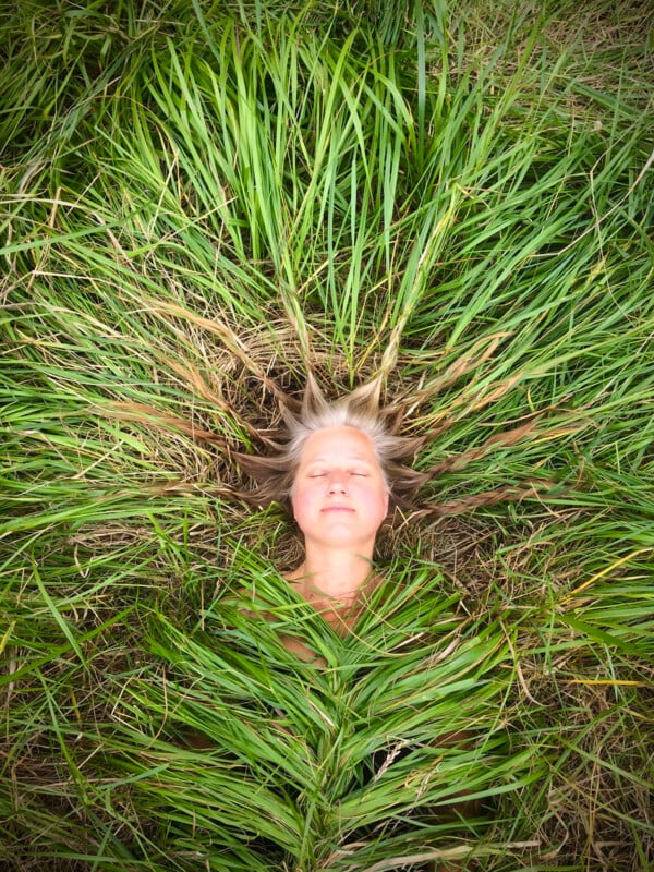 A woman weaved into the gras showing just her face. 