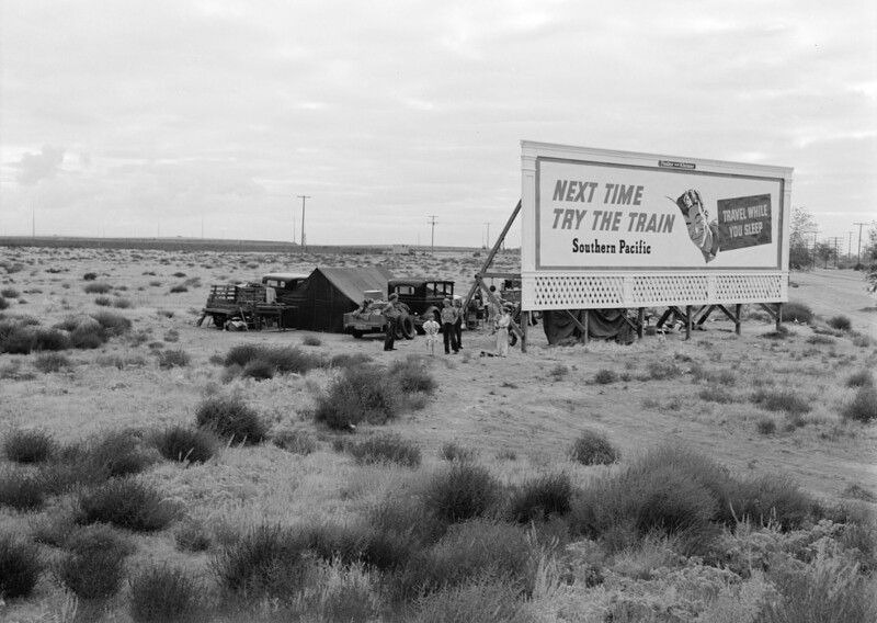 Three families camped behind an advertising billboard that serves as a windbreak