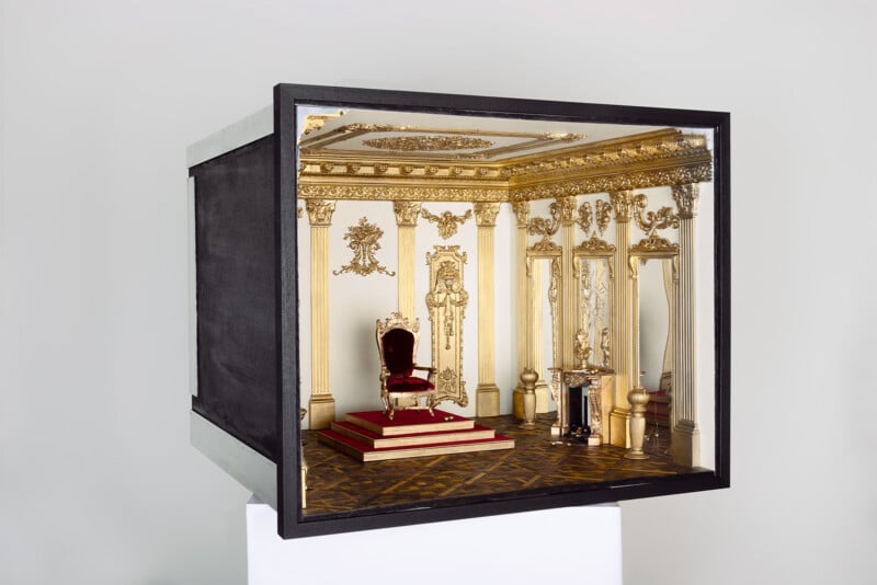Diorama of a classical throne room with a red velvet throne and gold trimmed columns 