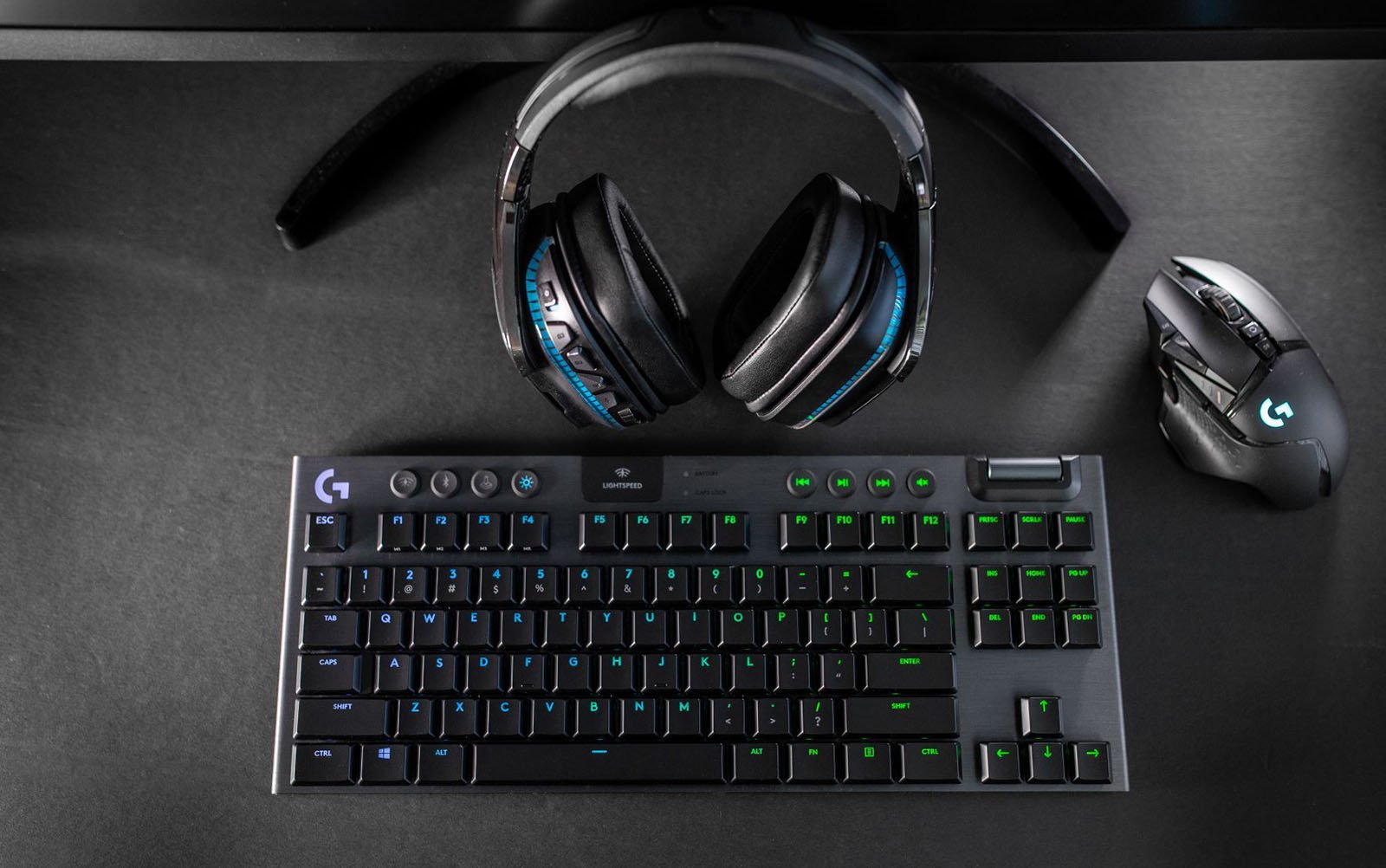 The Logitech G915 gaming keyboard is seen on a desk with a mouse and a pair of headphones.