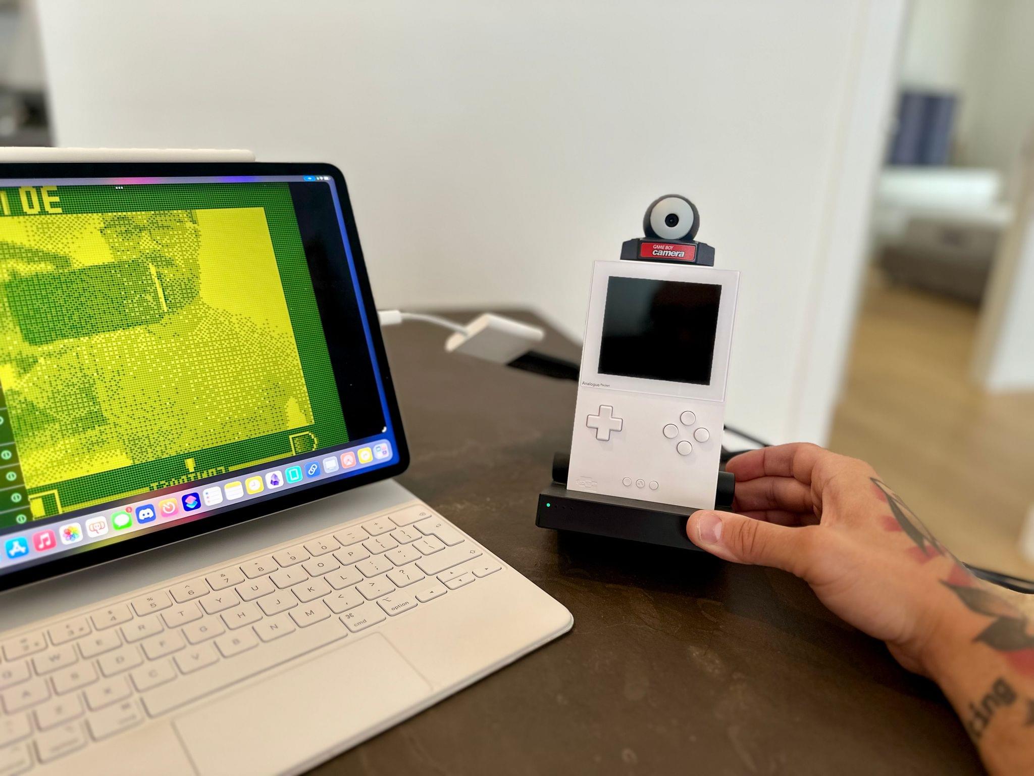 An iPad Pro mounted on a Magic keyboard and a Game Boy Camera in an Analogue Pocket are seen side by side on a desk.