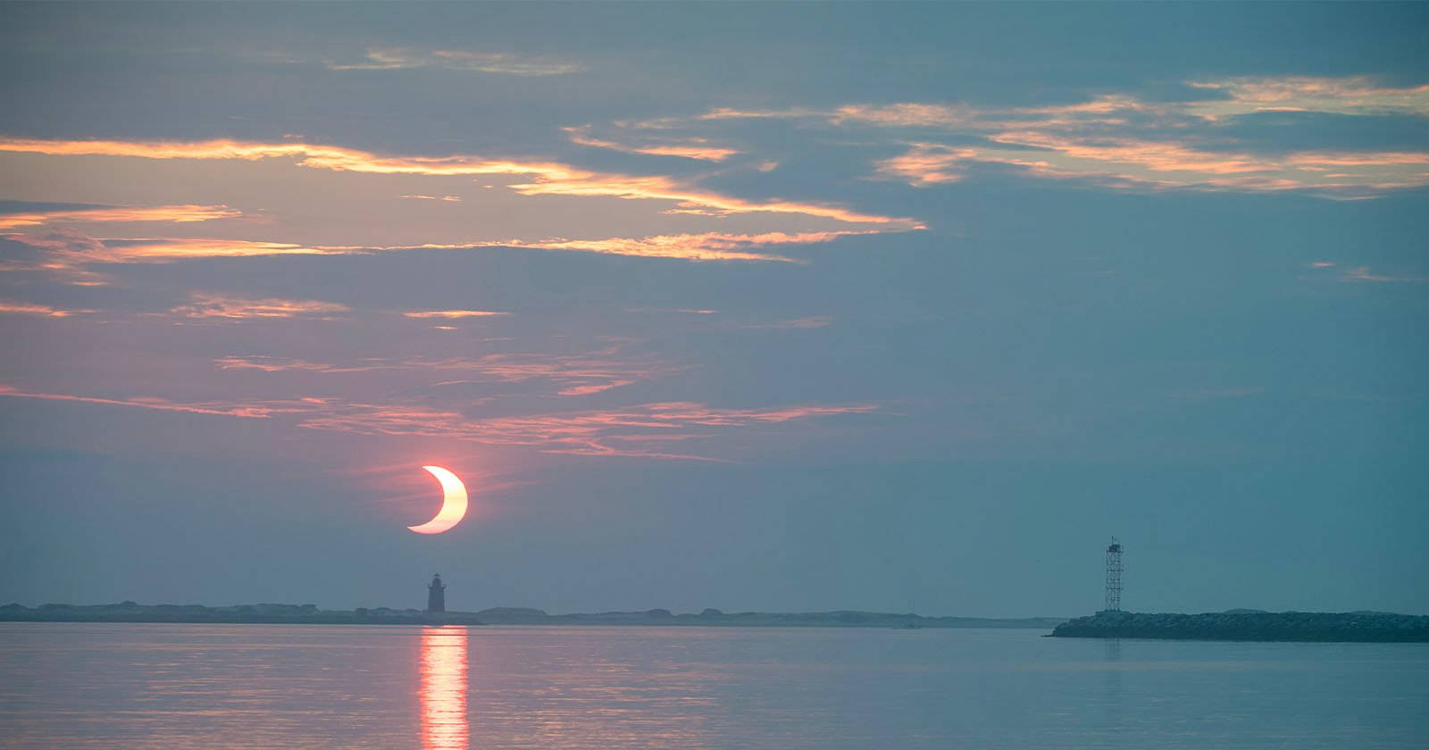 A partial eclipse is shown above a waterscape.