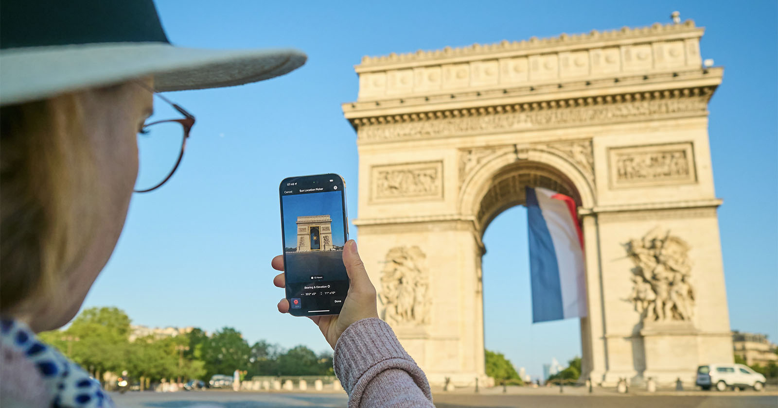 A woman takes a photo of the Arc de Triomphe using the Photo Scout app.