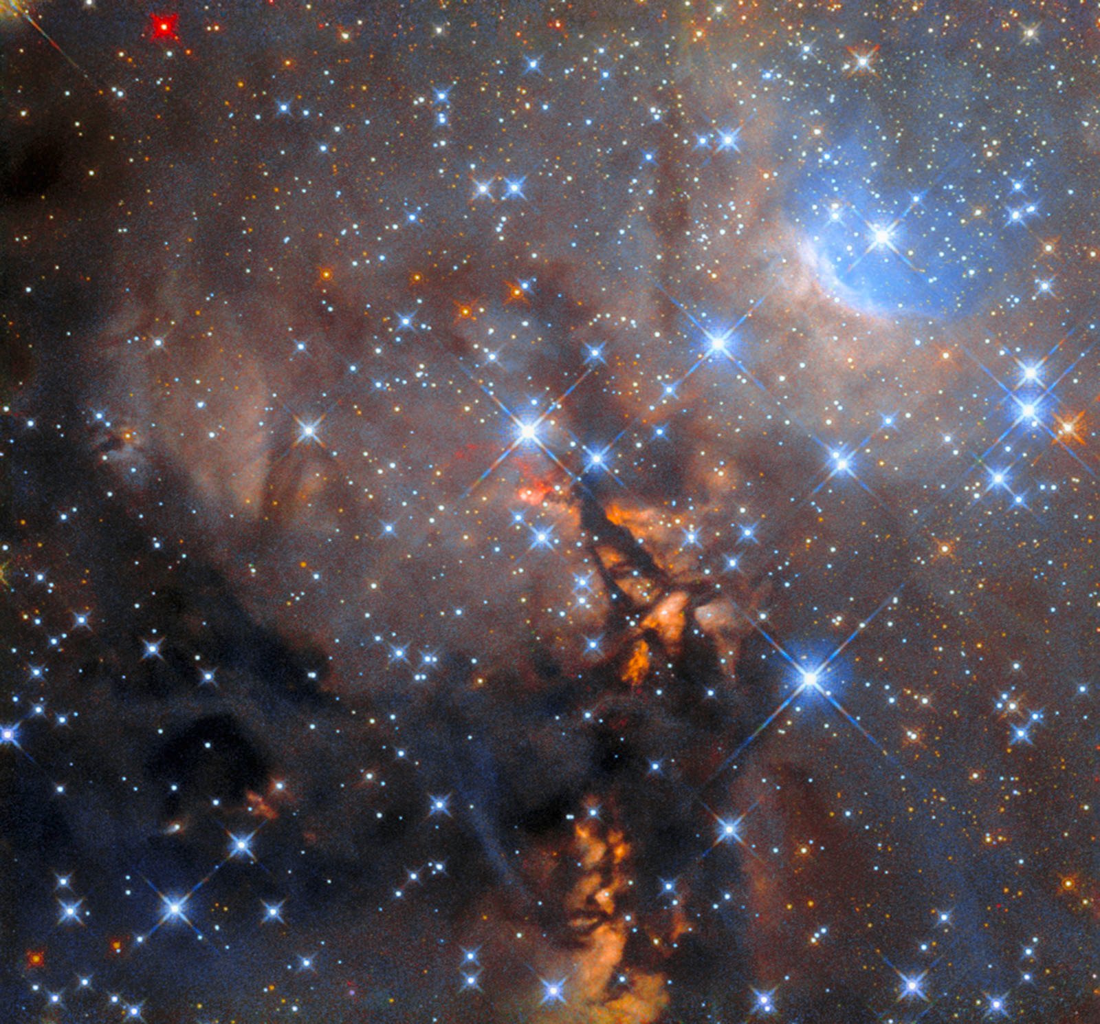The field is filled with hundreds of bright stars. They are primarily blue, with scattered smaller stars visible in yellow/orange. The background is dominated by cloudy grey dust, with permeating regions of dark black and orange.