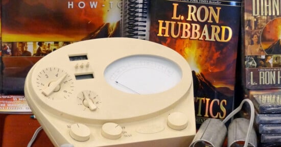 An "E-Meter" is seen in front of books by L. Ron Hubbard.