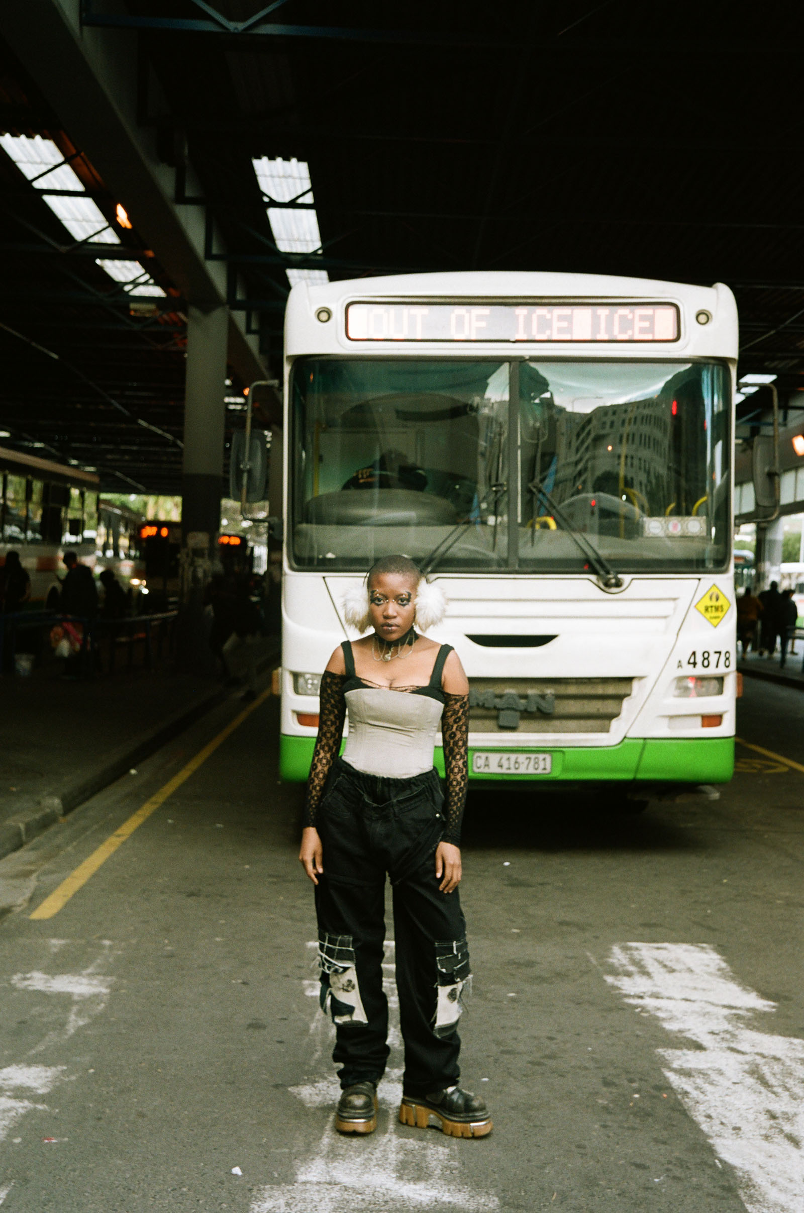 A woman poses, standing in front of a bus.