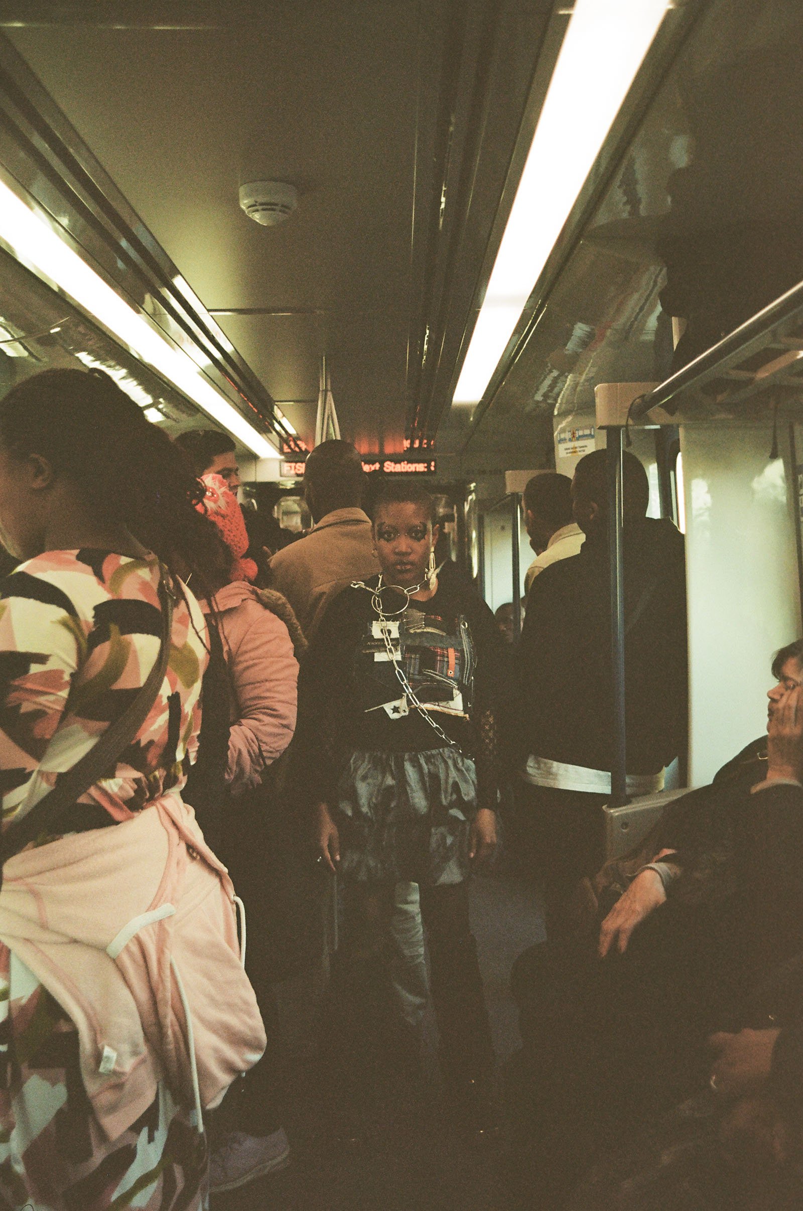 A woman poses amid a crowd of people on a busy train.