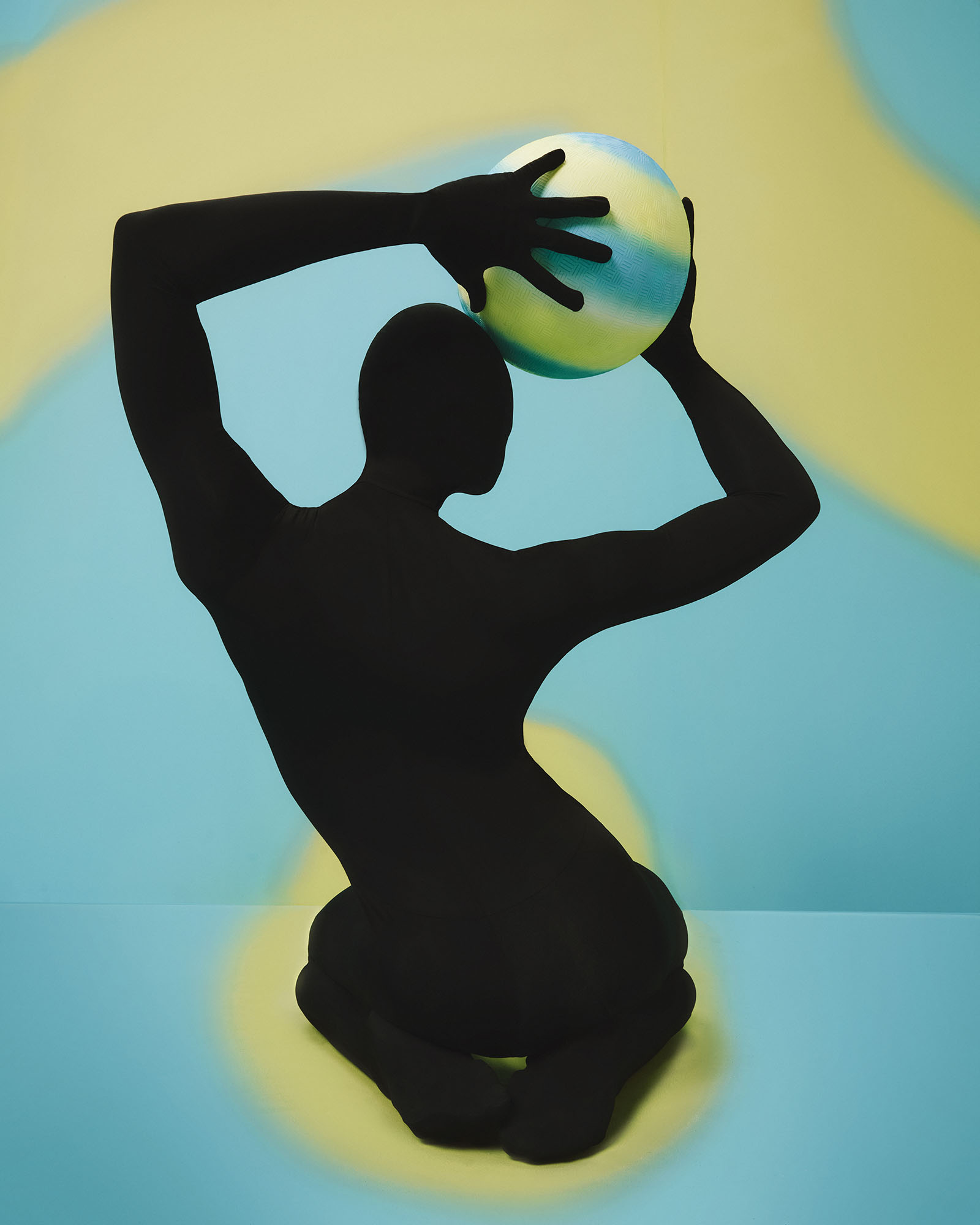 A silhouette holds a ball overhead.