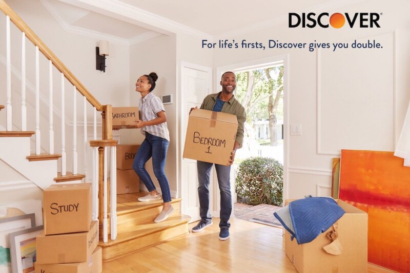 Tear sheet of two figures carrying labeled moving boxes into new home, smiling in the entryway, by Miami-based Corporate and Portrait Photographer Steve Boxall