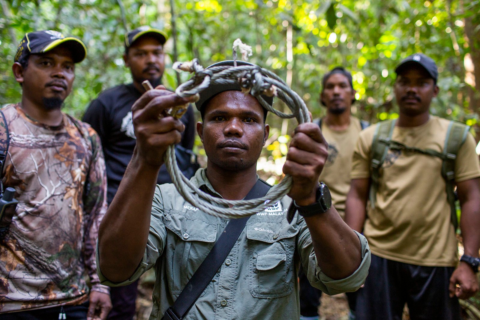 Anti-poaching patrol members hold up a collected snare.