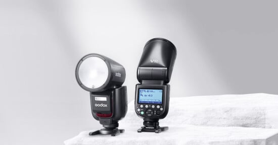 Two Godox V1Pro flashes sit on a white rock in front of a gray background.