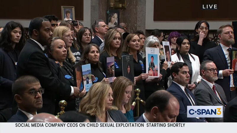 Audience members of the Senate Judiciary hearing on child safety online hold up photos of loved ones.