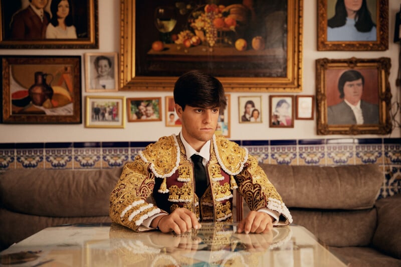 A Young Trainee Matador sits at the table in his Grandfathers home. His Grandfathers paintings surround him. David has been born in to a generational bullfighting family.