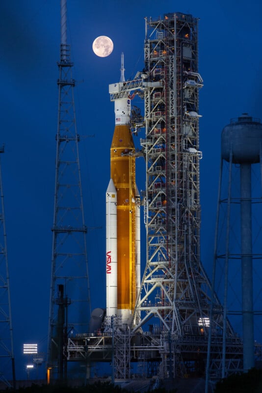 Spacecraft on launch pad in front of night sky, full Moon in background