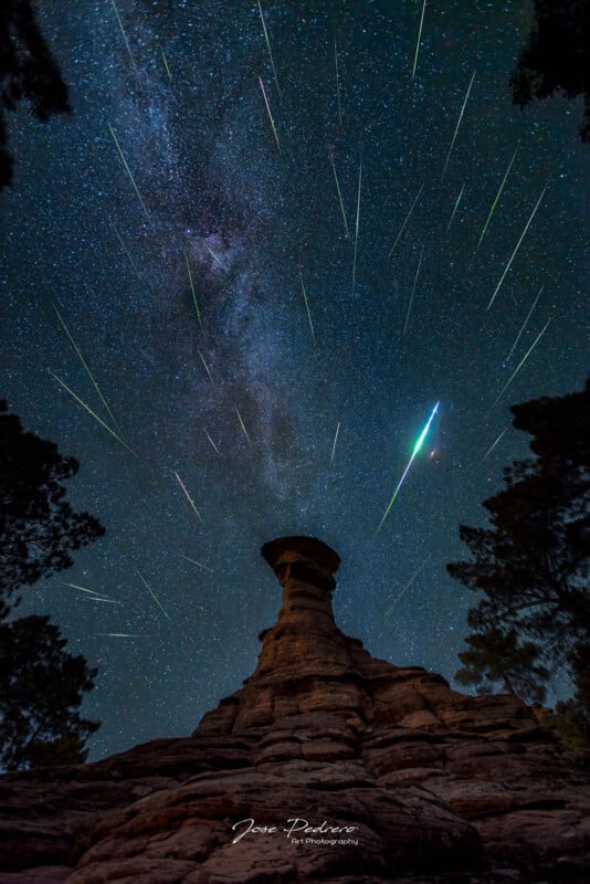 Multiple Perseid meteors against the night sky with a rock formation in the foreground