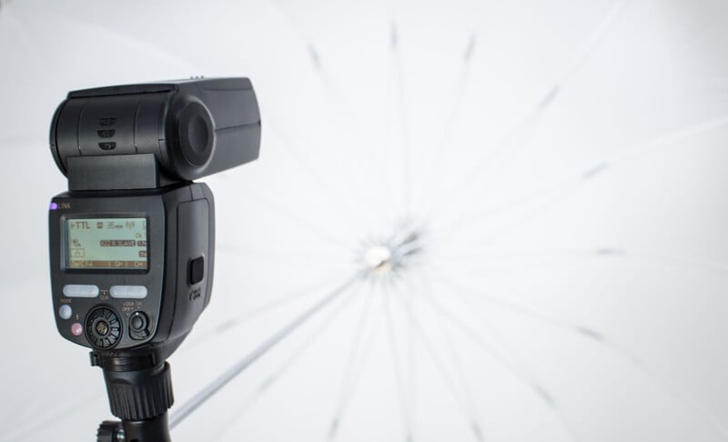 An external flash sits with a white umbrella attached. 