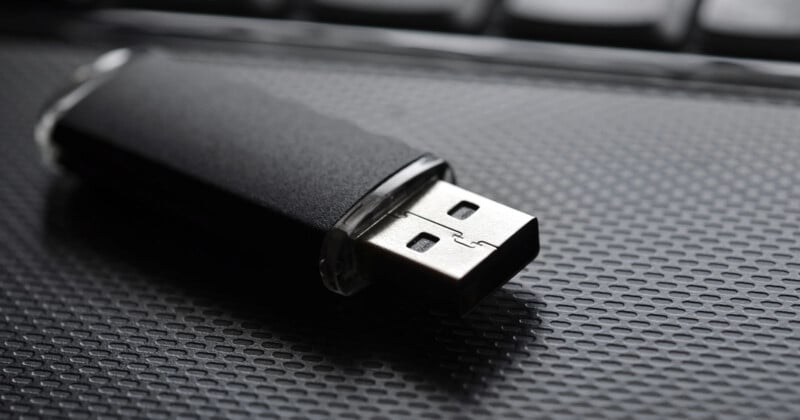 A black USB drive sits on a black laptop.