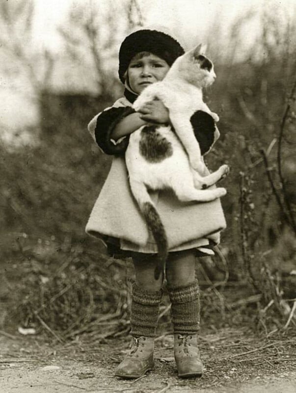 A young girl holding her cat. Early 20th century, rural. 