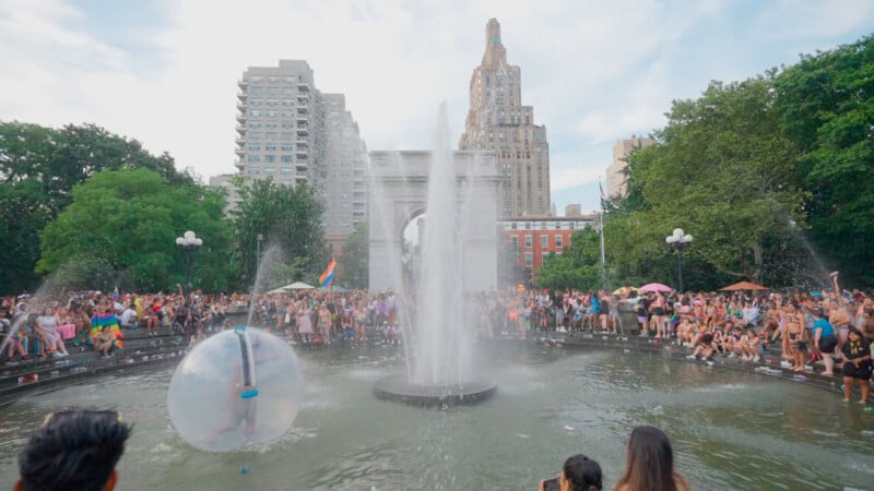 Washington Square Park in the summer with people around and the fountain on.