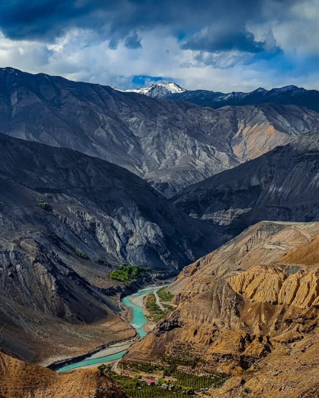 A turquoise river cuts through a steep mountain valley.