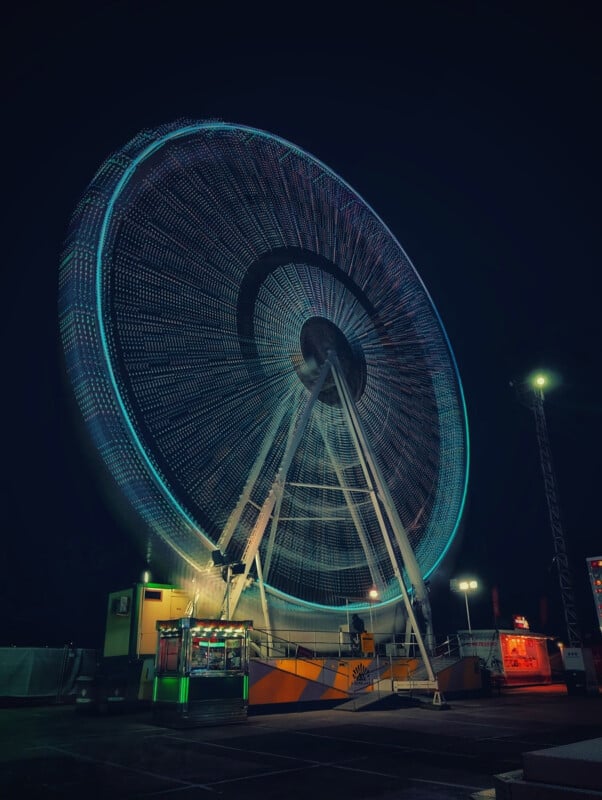 A ferris wheel's light blur while spinning at night. 
