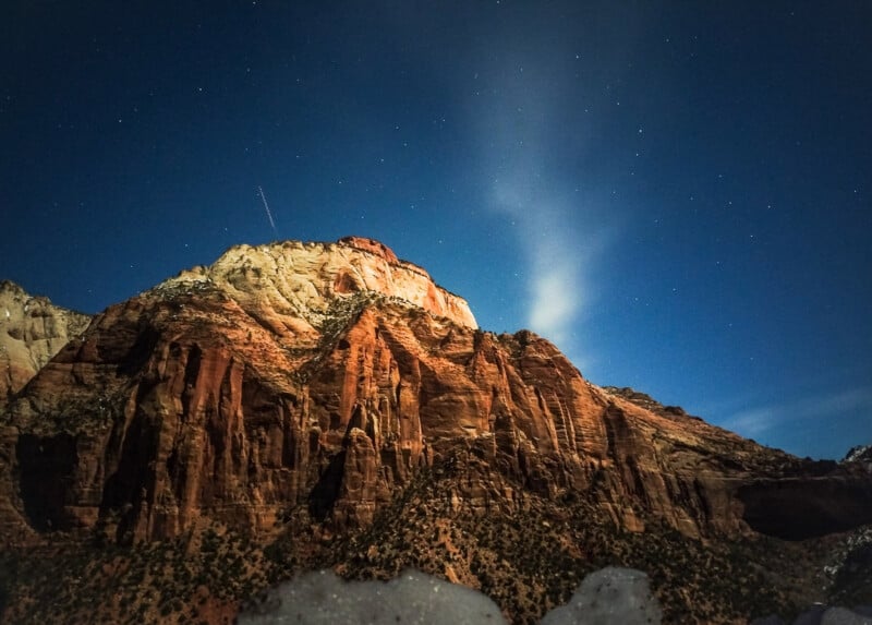 Red cliffs stand in front of a star-filled night sky.