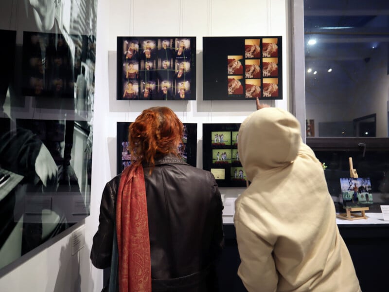 Two people look at art hung on a wall.