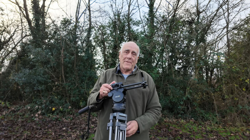 Photographer Mike Lane holds up his returned tripod outdoors.